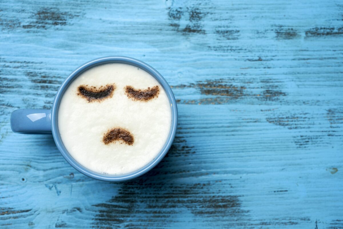 Cup of coffee with frowny face latte art